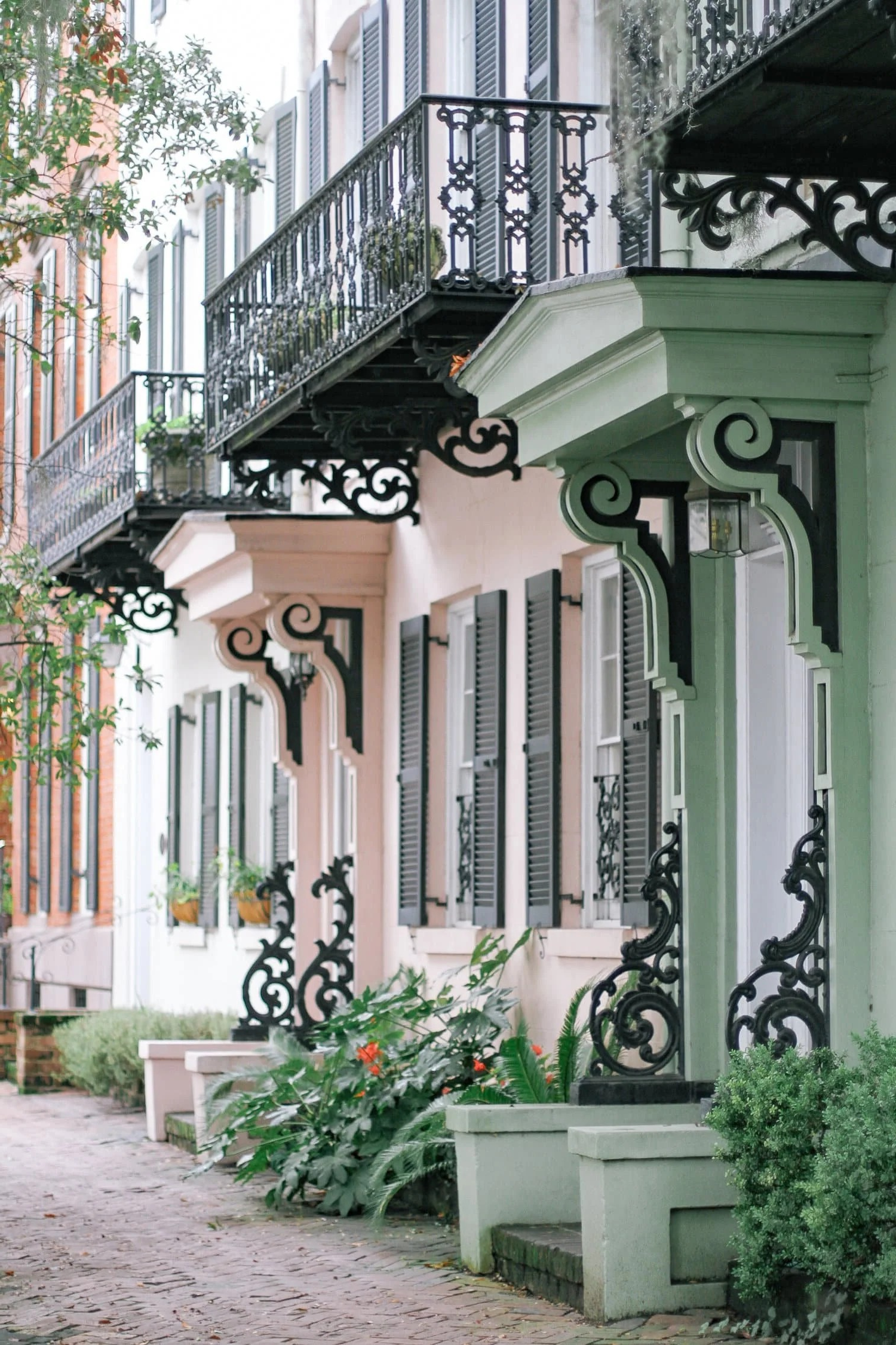 Historic Savannah townhouses with ornate cast-iron balconies and pastel facades along a cobblestone street